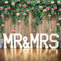 Large illuminated "MR & MRS" sign in front of a Spring Floral Wood Plank Photoshoot Flowers Backdrop - ideasbackdrop, expertly crafted by event decorators for a stunning floral backdrop.