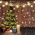 A decorated Christmas tree with string lights and ornaments stands in a wooden room, featuring an ideasbackdrop Rustic Glitter Background Wood Backdrop-ideasbackdrop. Wrapped gifts lie underneath, while snowflake decorations hang in the background, adding to the vintage design ambiance.