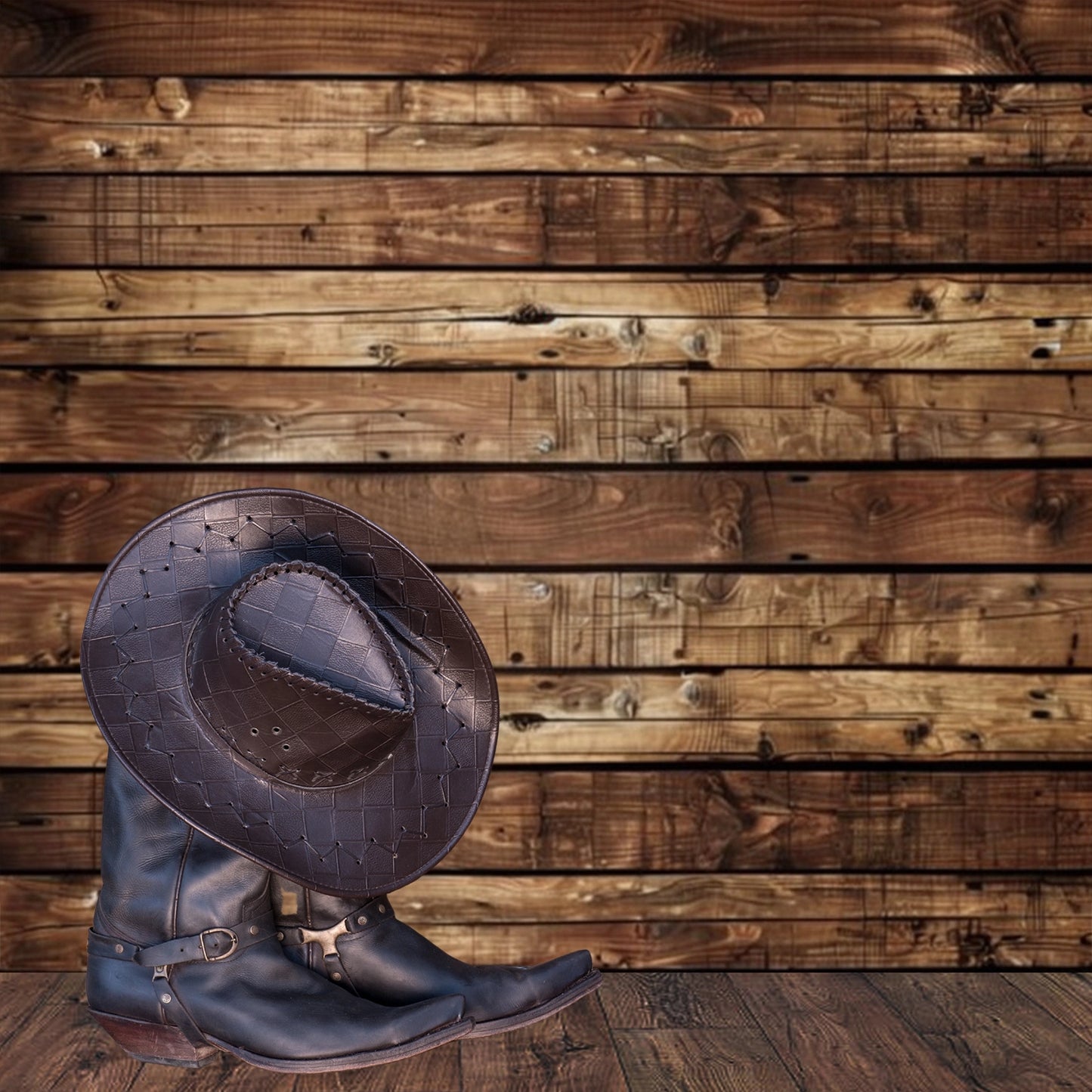 A brown cowboy hat and a pair of brown cowboy boots are placed on a wooden floor against the Wooden Boards Photography Wood Backdrop-ideasbackdrop by ideasbackdrop, giving the scene a nostalgic atmosphere.