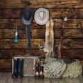 Western-themed decor with cowboy hats, boots, a lantern, guns, rope, and fur on a high-resolution *Rustic Wood Wall Backdrop Natural Brown Wooden Board Photography Background Baby Shower Birthday Party Cake Table Decor* by *ideasbackdrop* and hay bale background.