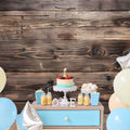 A first birthday setup with a cake, drinks, snacks, and balloons on a blue and white table against an ideasbackdrop 7x5ft Vintage Wood Backdrop Retro Rustic Wooden Floor Background for Photography Photo Booth Video Shoot Studio Props. The word "ONE" is displayed on the table.