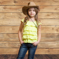 A young girl wearing a yellow ruffled top, blue jeans, and a brown cowboy hat stands against an ideasbackdrop 7x5ft Wooden Backdrop Baby Shower Wood Wall Background Party Decorations Props for Photographers Studio.