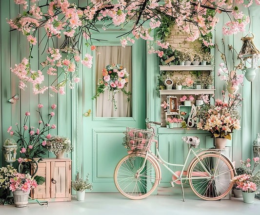 A mint-green door with a wreath is surrounded by pink flowers and plants, creating an HD vivid floral backdrop. A vintage bicycle with a basket stands in front, alongside shelves of potted plants and flowers—ideal for photo sessions or weddings using the Bicycle Blossom Photography Flower Backdrop-ideasbackdrop by ideasbackdrop.