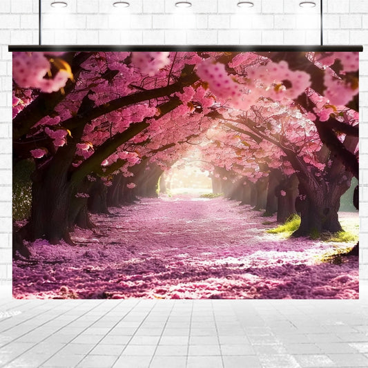 An outdoor path is lined with Cherry Blossom Boulevard Floral Backdrops - ideasbackdrops in full bloom, their pink petals covering the ground. Sunlight filters through the branches, creating a serene and picturesque scene, making it an Instagram-worthy setting.