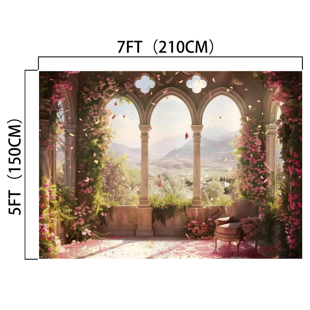 A 7ft by 5ft European Style Window Flower Backdrop - ideasbackdrop featuring an elegant, ivy-covered archway overlooking a scenic view with mountains, greenery, and scattered pink flowers. Perfect for weddings, it includes a vintage chair to the right.