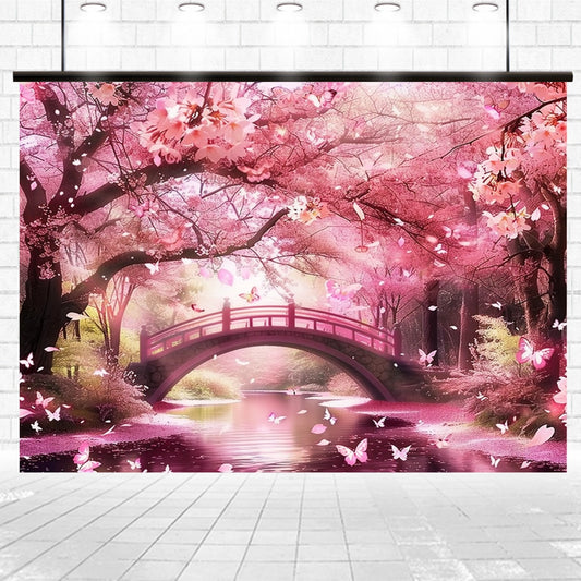 A serene scene featuring a pink flowered bridge over a tranquil stream, surrounded by cherry blossom trees and butterflies, creates the ideasbackdrop Floral Cherry Blossom Bridge Flower Backdrop -ideasbackdrop ideal for professional photo shoots.