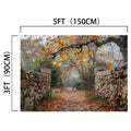A stone pathway with a metal gate and overhanging tree branches adorned with autumn leaves sets the perfect scene for fall portraits. A bicycle is visible in the background, adding to the charm of this Gate Stone Wall Autumn Leaves Trees Fall Backdrop-ideasbackdrop. Dimensions are 5ft (150cm) by 3ft (90cm).