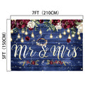 A premium quality backdrop with dimensions of 7ft by 5ft (210cm by 150cm), featuring "Mr & Mrs" text, flowers, and string lights against a dark blue wooden background—perfect as a wedding decoration. This is the Mr and Mrs Flower Rustic Wedding Backdrop-ideasbackdrop from ideasbackdrop.