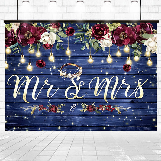 A decorative "Mr & Mrs" sign with floral and string light embellishments on a premium quality wooden backdrop, featuring a ring in the design, called the Mr and Mrs Flower Rustic Wedding Backdrop-ideasbackdrop by ideasbackdrop.