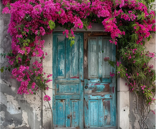 A weathered blue door, adorned with vibrant pink flowers cascading from above and around the frame, creates a beautiful home decor piece against a textured, aged wall. The Spring Flowers Old Wood Door Backdrop-ideasbackdrop by ideasbackdrop offers a charming door backdrop for any space.