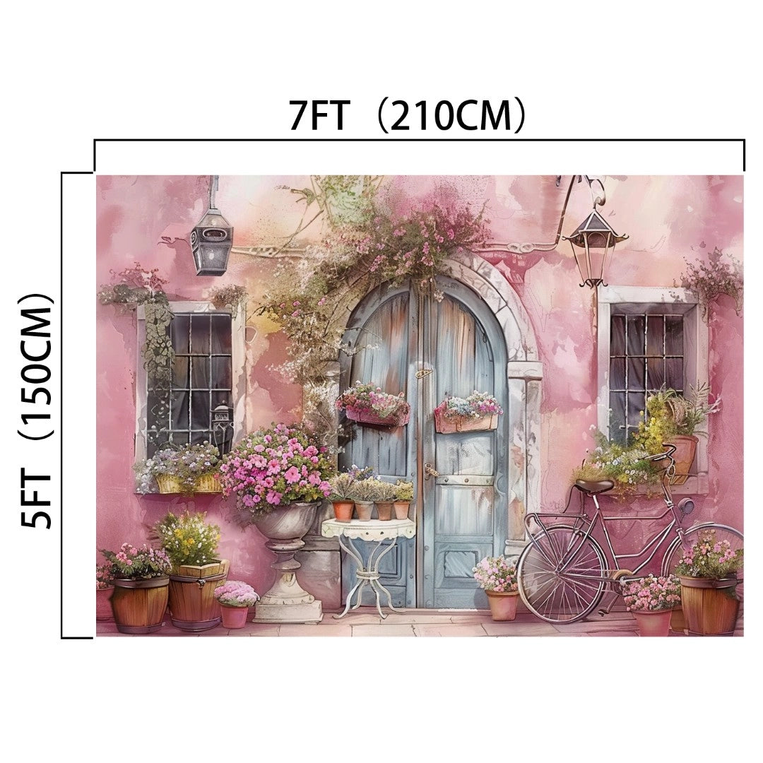 A quaint outdoor scene with potted flowers surrounding a large, arched blue door on a pink building creates dramatic decor. Nearby, an old bicycle with a basket adds charm. This Pink Wall Flower Spring Nature Door Backdrop-ideasbackdrop by ideasbackdrop measures 7 feet (210 cm) wide and 5 feet (150 cm) tall, perfect for a photo backdrop.