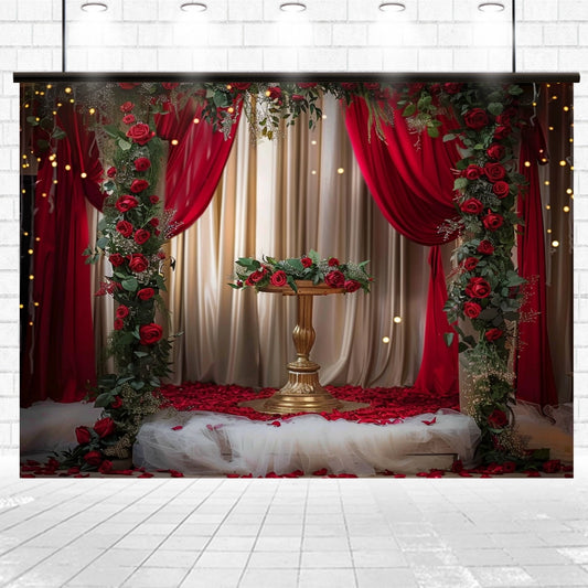 A decorative setup featuring a pedestal table adorned with red roses, surrounded by red and white curtains, with a rose petal-covered floor beneath strings of fairy lights creates the perfect Red Floral Wedding Bridal Shower Backdrop - ideasbackdrop. Ideal for floral photography or any elegant event setting.