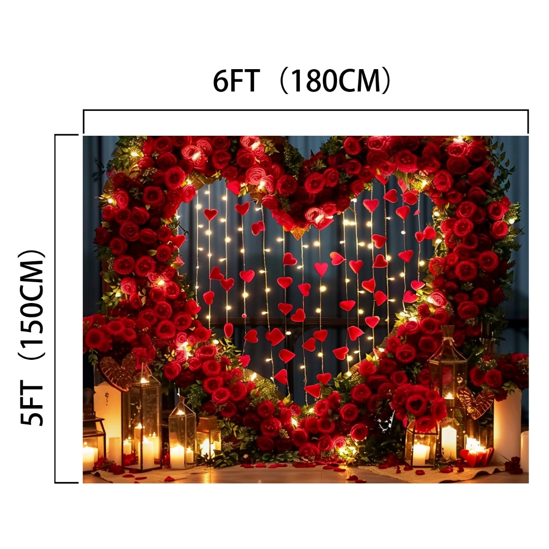 A heart-shaped arrangement of lifelike red roses is illuminated by strings of lights and red heart decorations. Candle-lit lanterns are placed around the setup, creating a romantic ambiance, enhanced by a Red Rose Heart Arch Photography Backdrop from ideasbackdrop that adds depth and charm to the scene.
