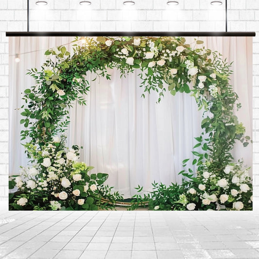 A Romantic Flower Wreath Bridal Wedding Backdrop-ideasbackdrop from ideasbackdrop with white flowers and green leaves stands against a white curtain backdrop in a well-lit room, creating the perfect wedding backdrop for picture-perfect moments.