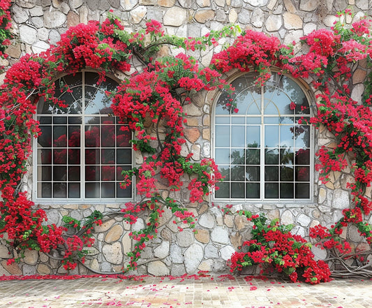 Stone building facade with two arched windows partially covered by vibrant red flowering vines, creating a picturesque Romantic Red Blossom Flower House Windows Backdrop-ideasbackdrop for photographers by ideasbackdrop.