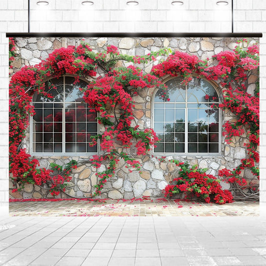 A stone wall with two arched windows is adorned with vibrant red flowering plants, creating the perfect photography backdrop. Some of the red petals have fallen onto the ground below, enhancing the studio atmosphere for any shoot.