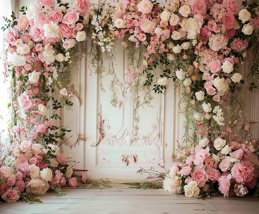 An ornate floral arch made of pink and white roses, peonies, and greenery serves as a Romantic Wedding Bridal Floral Wall Backdrop -ideasbackdrop. The high-definition flowers frame an elegant, detailed wall, while the floor is wooden.
