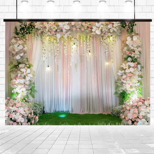 A Romantic Wedding Floral Backdrop for Photography Studio featuring draped white curtains adorned with lifelike vivid flowers in pink and white, greenery, and soft hanging lights. This floral masterpiece by ideasbackdrop is set against a white brick wall with a green grass floor, creating an enchanting atmosphere.