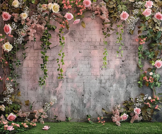 A brick wall is adorned with hanging ivy and an array of pink and white roses, along with small pink flowers, all depicted in vibrant colors. The ground is covered with grass. This Spring Flower Brick Wall Photography Backdrop by ideasbackdrop brings a lifelike touch to any setting.