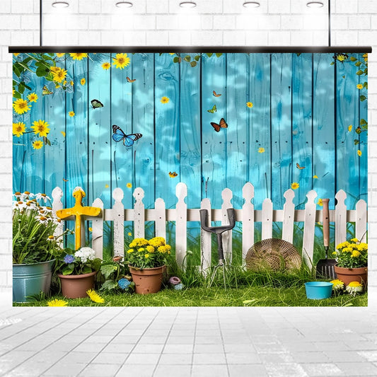 A decorative garden scene with flowers, potted plants, and garden tools in front of a white picket fence and blue wooden background adorned with butterflies and sunflowers, perfect for wedding celebrations or photo shoots with a Spring Garden Wood Fence Flower Backdrop -ideasbackdrop by ideasbackdrop.
