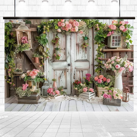 A rustic wooden door adorned with pink and white flowers is surrounded by wooden crates and lanterns featuring additional floral arrangements. This charming setup, set against a white brick wall and floor, creates a Spring Rose Floral Wooden Door Flower Backdrop -ideasbackdrop ideal for weddings.
