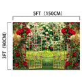 A decorative metal gate adorned with red roses is set in a lush garden background, perfect for weddings or photo shoots. The gate, measuring 5 feet (150 cm) wide and 3 feet (90 cm) tall, serves as an ideasbackdrop Spring Garden Wedding Rose Flower Backdrop -ideasbackdrop.